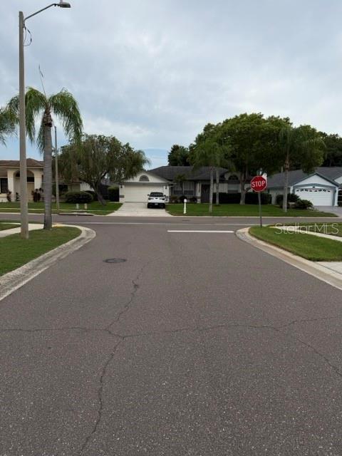 A residential street leads toward a house with a stop sign in the foreground — 588 HOLLOWTREE PLACE, TARPON SPRINGS, FL