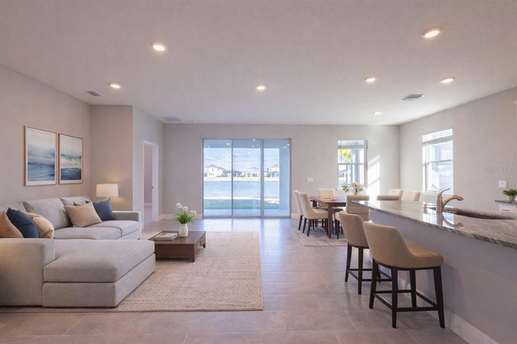 An open-concept living and dining area features tile floors, a kitchen island, and sliding doors — 345 MANGROVE MANOR DRIVE, APOLLO BEACH, FL