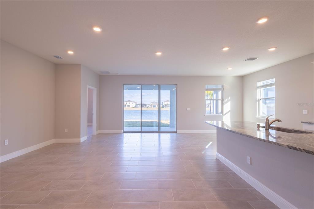 An open-concept living area features tile flooring, recessed lighting, and sliding glass doors to water — 345 MANGROVE MANOR DRIVE, APOLLO BEACH, FL