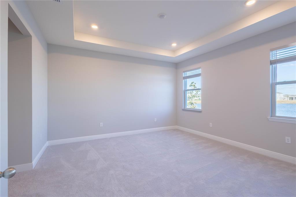 An empty bedroom features light gray walls, carpeted flooring, and a recessed tray ceiling — 345 MANGROVE MANOR DRIVE, APOLLO BEACH, FL