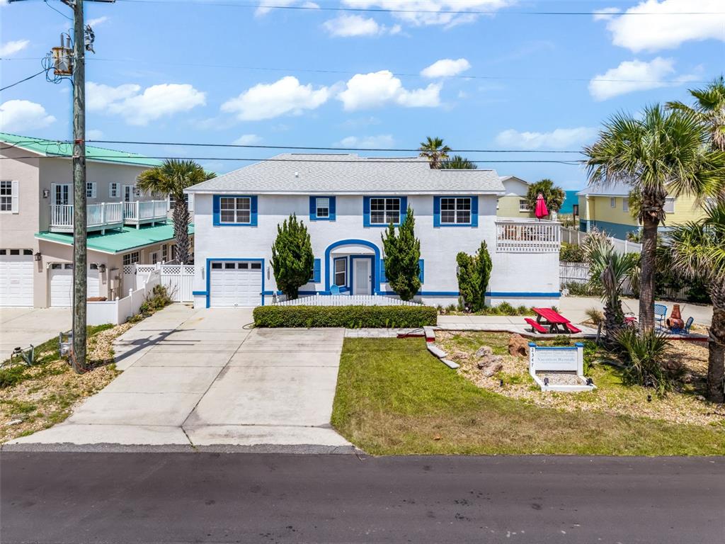 A two-story white house with blue trim features a driveway, lawn, and palm trees — 2347 S CENTRAL AVENUE, FLAGLER BEACH, FL