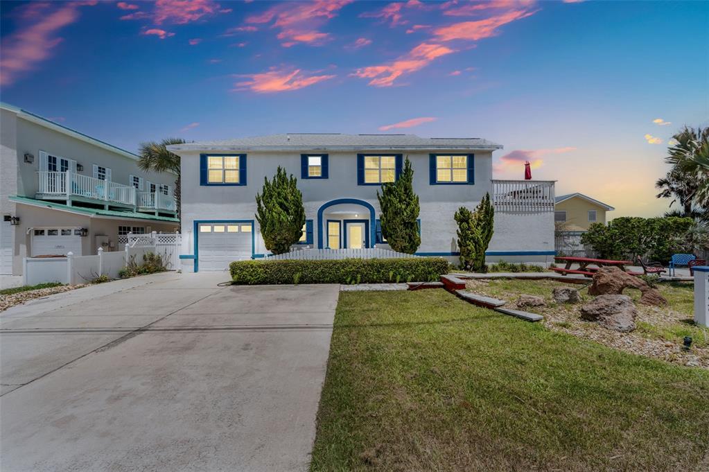 A two-story house with a white exterior, blue trim, and a concrete driveway at sunset — 2347 S CENTRAL AVENUE, FLAGLER BEACH, FL