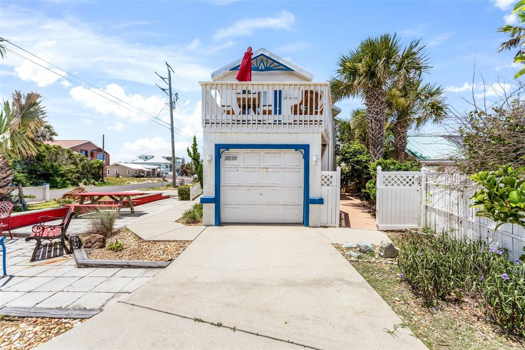 A two-story beach house with a white garage door, a balcony, and a red umbrella — 2347 S CENTRAL AVENUE, FLAGLER BEACH, FL