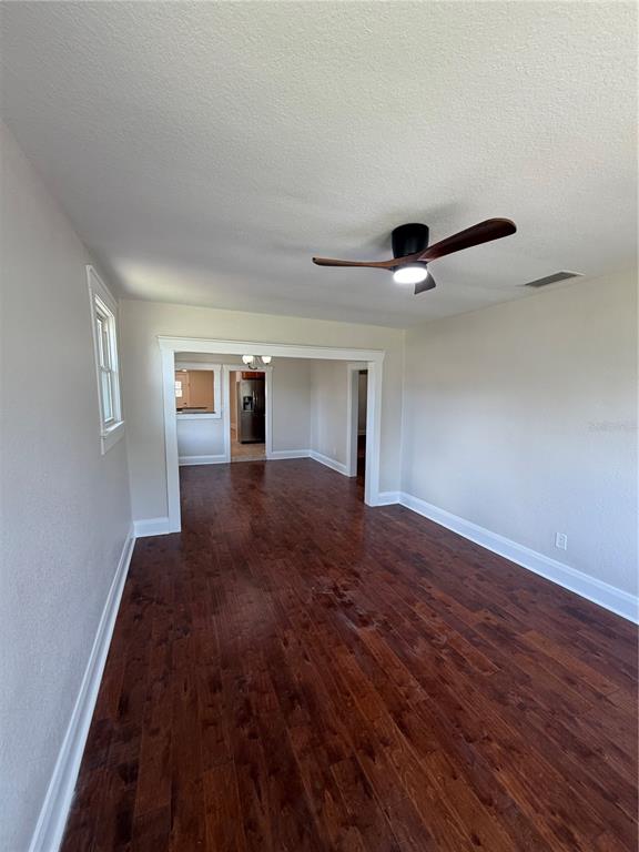 An interior view of a room with dark wood flooring, white walls, and a ceiling fan — 919 W PLYMOUTH STREET, TAMPA, FL