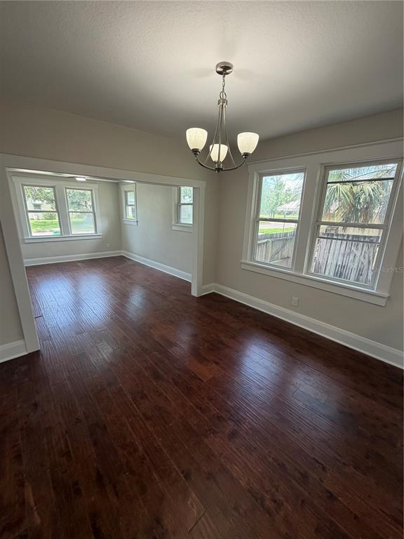 A dining room with dark wood flooring, a chandelier, and an open doorway to another room — 919 W PLYMOUTH STREET, TAMPA, FL