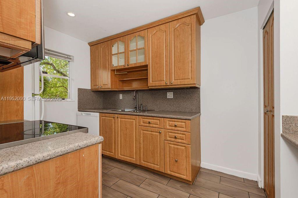 A kitchen features light wood cabinets, a speckled countertop, and a window above the sink — 4111 Stirling Rd # 308, Dania Beach FL 33314, DANIA BEACH, FL
