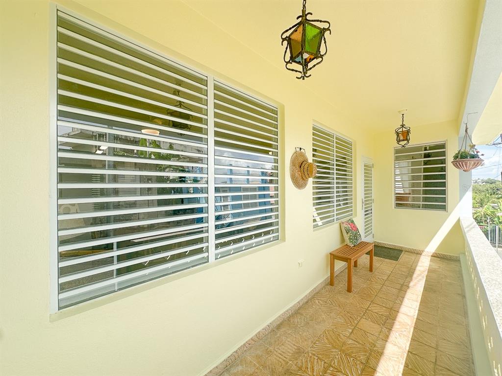 A covered balcony features tiled flooring, louvered windows, and decorative hanging lanterns — 272 BUENA VISTA, VIEQUES, PR