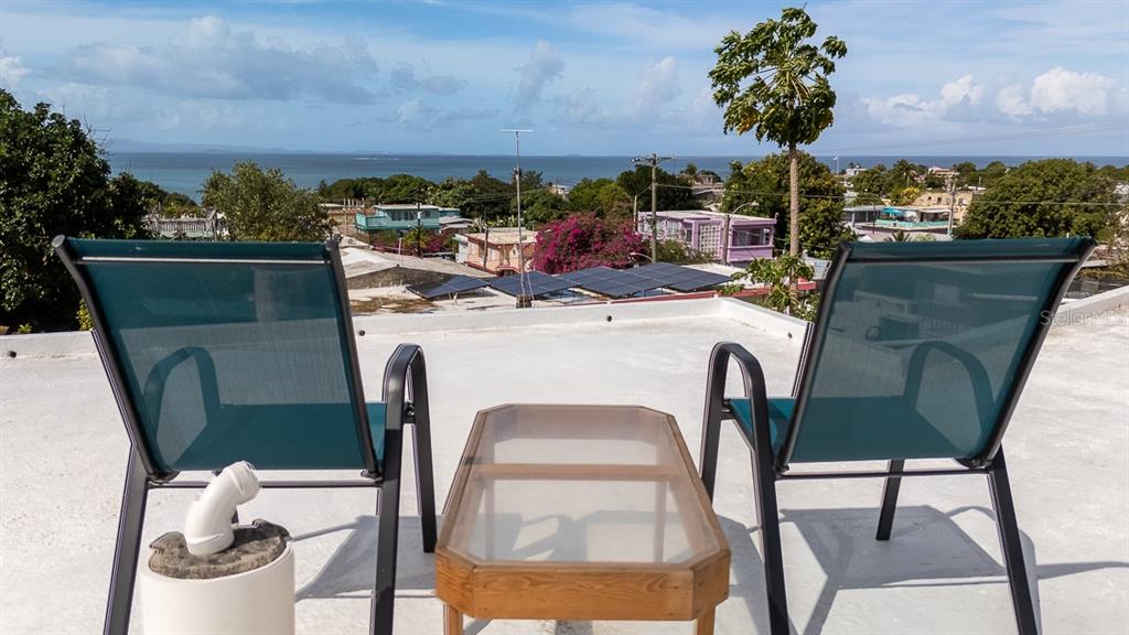 Two chairs and a glass table sit on a rooftop terrace overlooking the ocean — 272 BUENA VISTA, VIEQUES, PR