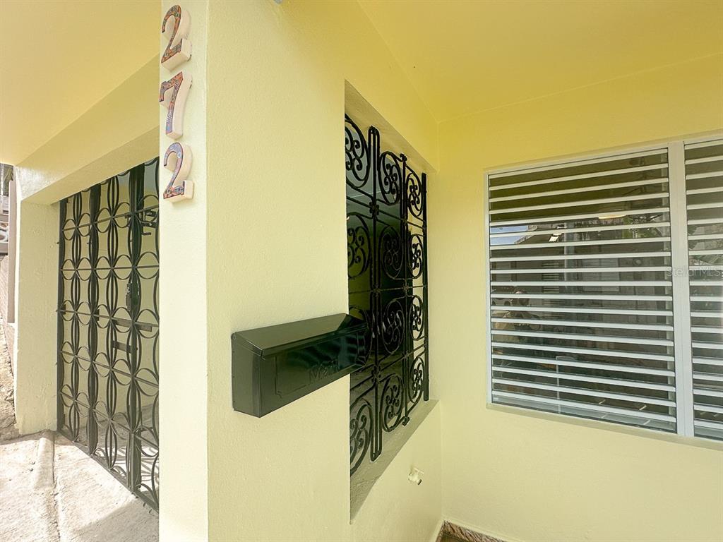 A covered porch features a black metal security gate, a mailbox, and a window with louvers — 272 BUENA VISTA, VIEQUES, PR