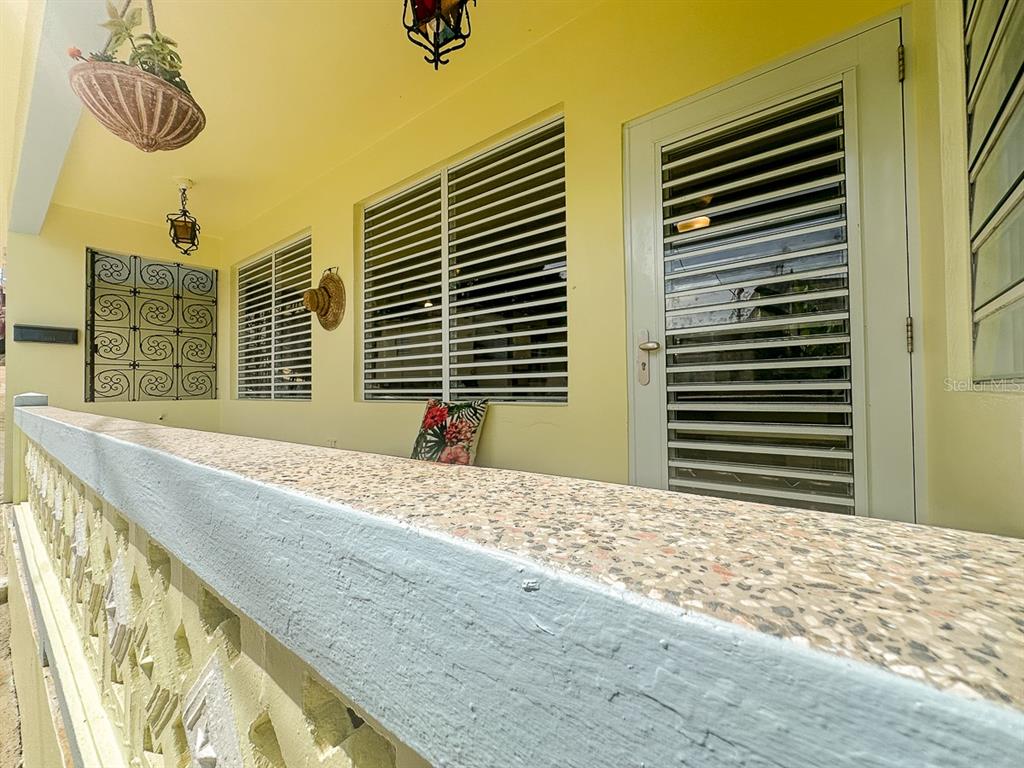 A covered porch features a terrazzo-topped wall, louvered windows, and a white door — 272 BUENA VISTA, VIEQUES, PR