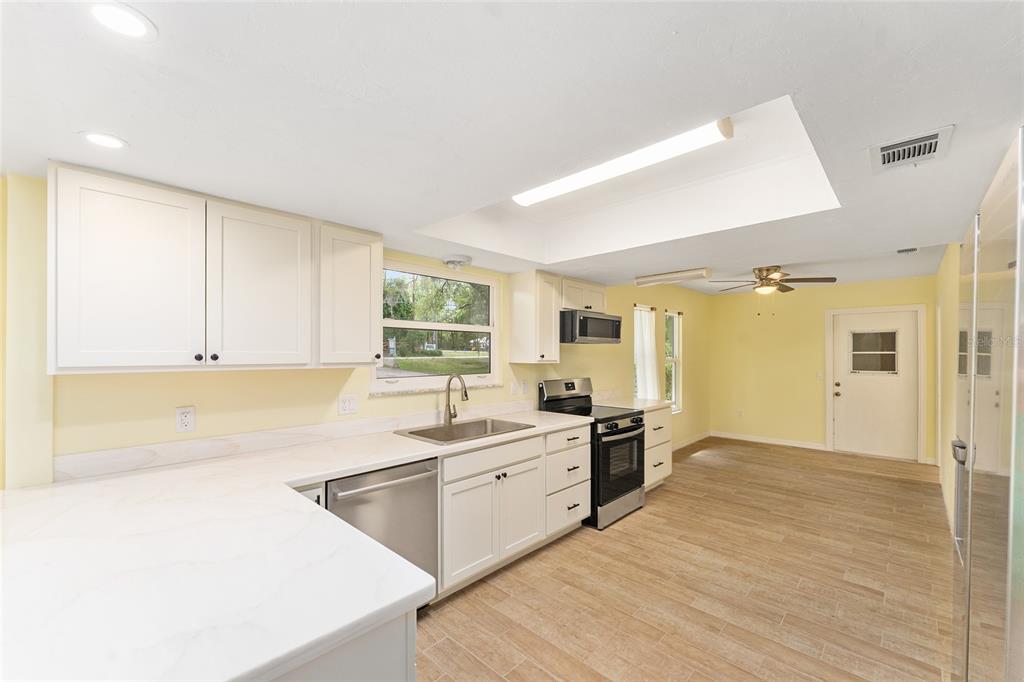 A dining area with a light wood table opens into a living room with vaulted ceilings — 813 SW 99TH STREET, GAINESVILLE, FL