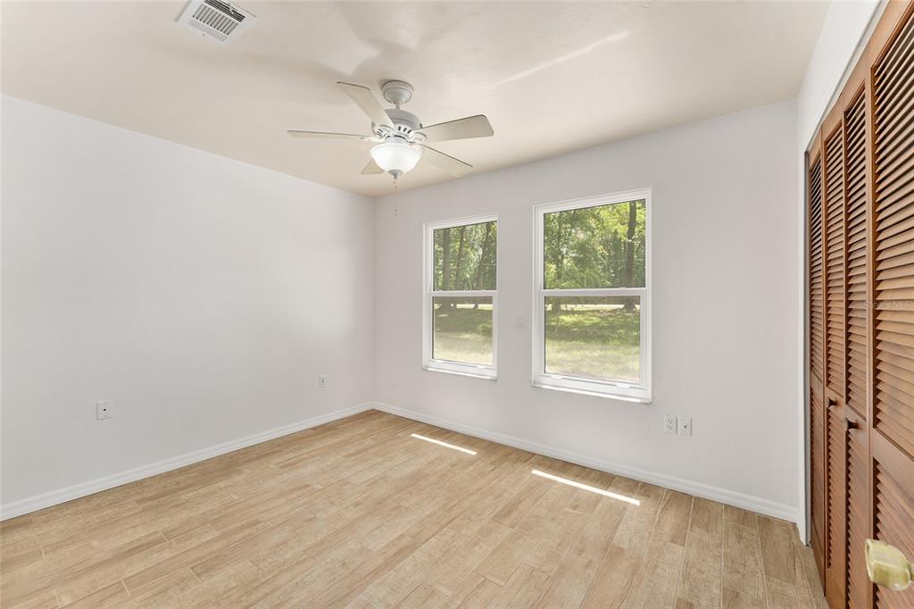 A living room with light yellow walls, wood-look tile flooring, and a vaulted wood ceiling — 813 SW 99TH STREET, GAINESVILLE, FL