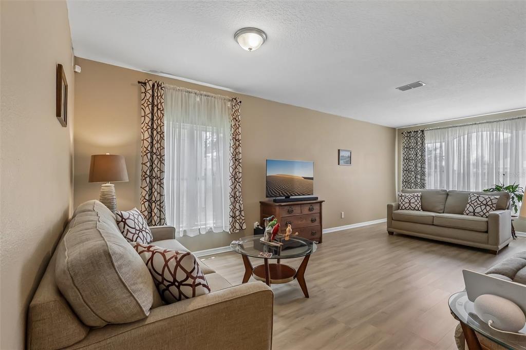 A living room features light wood-look flooring, two beige sofas, and a central glass coffee table — 34046 ALAMEDA DRIVE, SORRENTO, FL