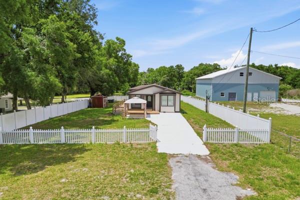 An exterior view of a single-story house with a white fence and a detached garage — 1140 S FLORIDA AVENUE, WAUCHULA, FL