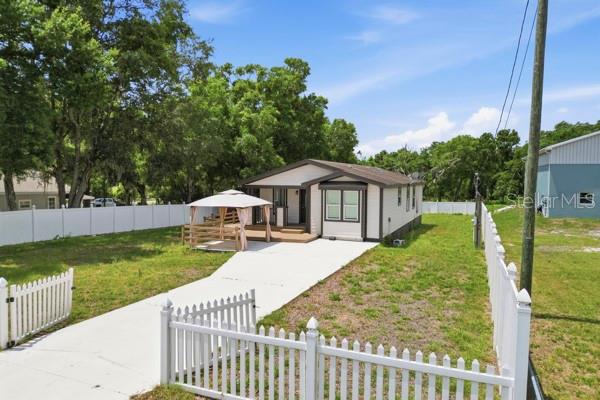 A single-story house with a white fence, a concrete driveway, and a gazebo in the yard — 1140 S FLORIDA AVENUE, WAUCHULA, FL
