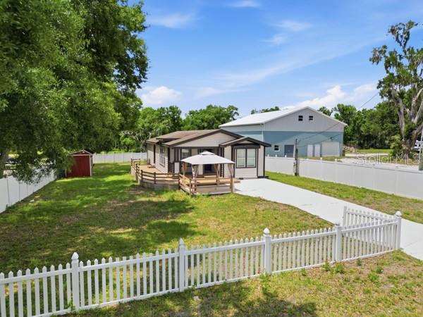 An exterior view of a house with a wooden deck, gazebo, and white vinyl fence — 1140 S FLORIDA AVENUE, WAUCHULA, FL