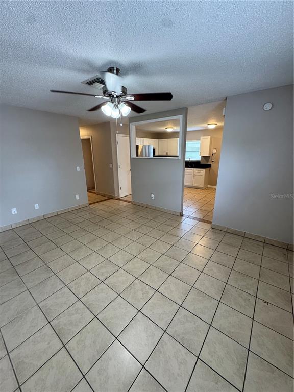 A living area with tile flooring and a ceiling fan opens to a kitchen — 1801 17TH STREET, ST CLOUD, FL