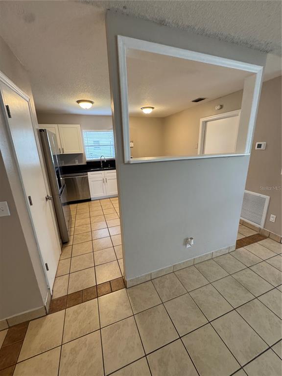 A kitchen with white cabinets and stainless steel appliances is visible through a wall cutout — 1801 17TH STREET, ST CLOUD, FL