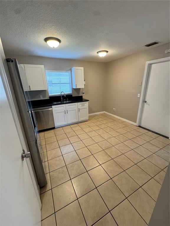 A kitchen features white cabinets, stainless steel appliances, a window, and light-colored tile flooring — 1801 17TH STREET, ST CLOUD, FL