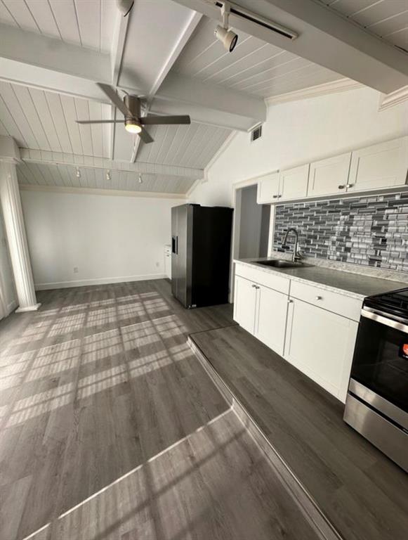 A kitchen with white cabinets, a black refrigerator, and gray wood-look flooring under vaulted ceilings — 1895 SW LITTLE ROAD UNIT E, LAKE CITY, FL