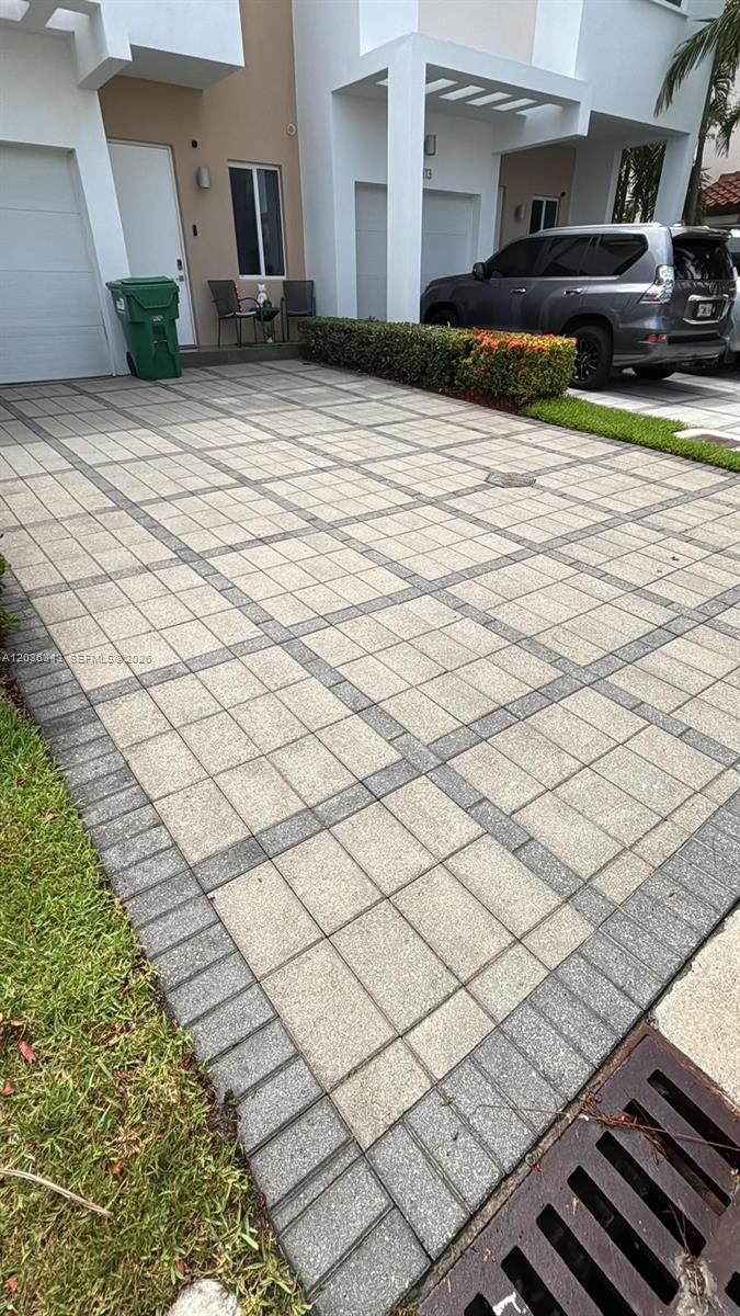 A paved driveway leads to the entrance of a modern two-story residential building — 7117 NW 103rd Path, Doral FL 33178, DORAL, FL