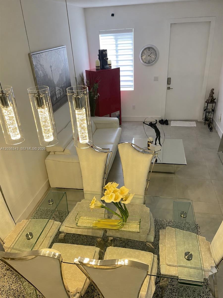 A dining area with a glass table and chairs sits in front of a living room — 7117 NW 103rd Path, Doral FL 33178, DORAL, FL
