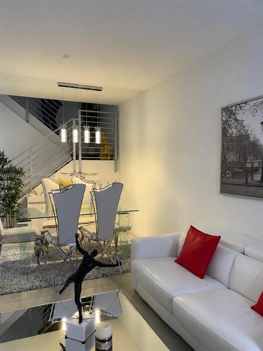 A dining area with a glass table and modern chairs sits beside a white sofa — 7117 NW 103rd Path, Doral FL 33178, DORAL, FL