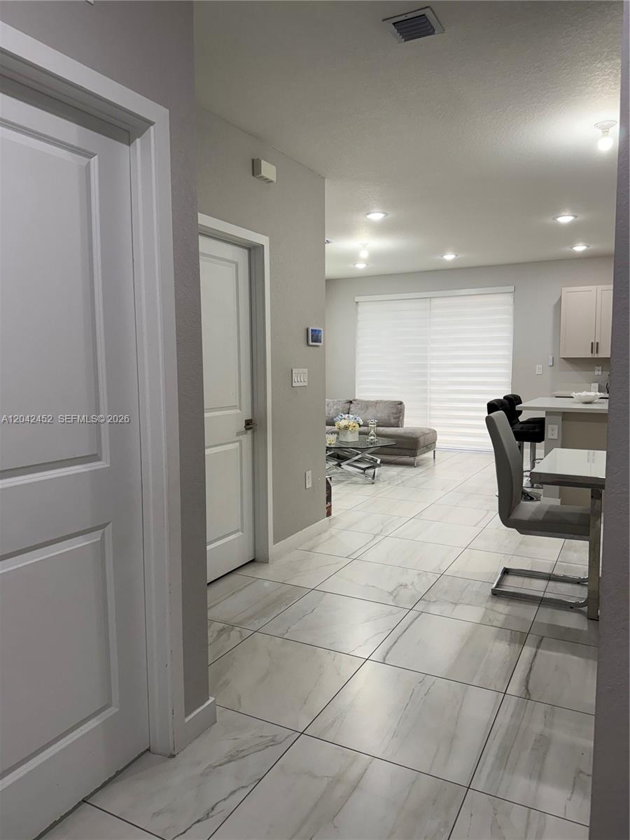 A view from a hallway looking into an open-concept living area with tiled floors — 1034 SE 23rd Ter, Homestead FL 33035, HOMESTEAD, FL