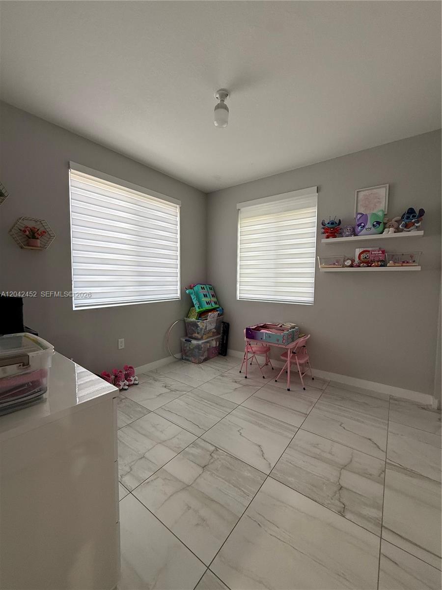 A child's playroom features light gray walls, white tile flooring, and two windows with blinds — 1034 SE 23rd Ter, Homestead FL 33035, HOMESTEAD, FL