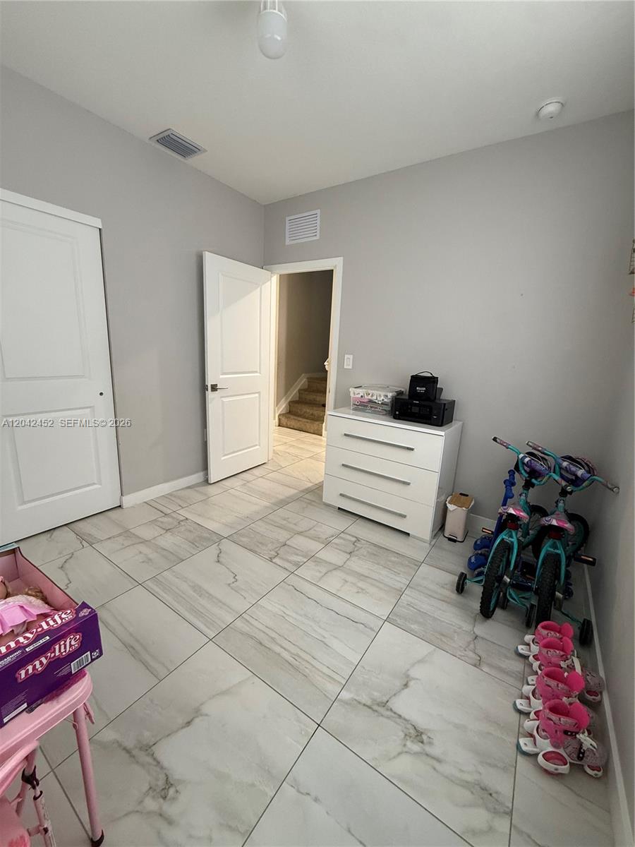 A room with light gray walls, white tile flooring, a white dresser, and two bicycles — 1034 SE 23rd Ter, Homestead FL 33035, HOMESTEAD, FL