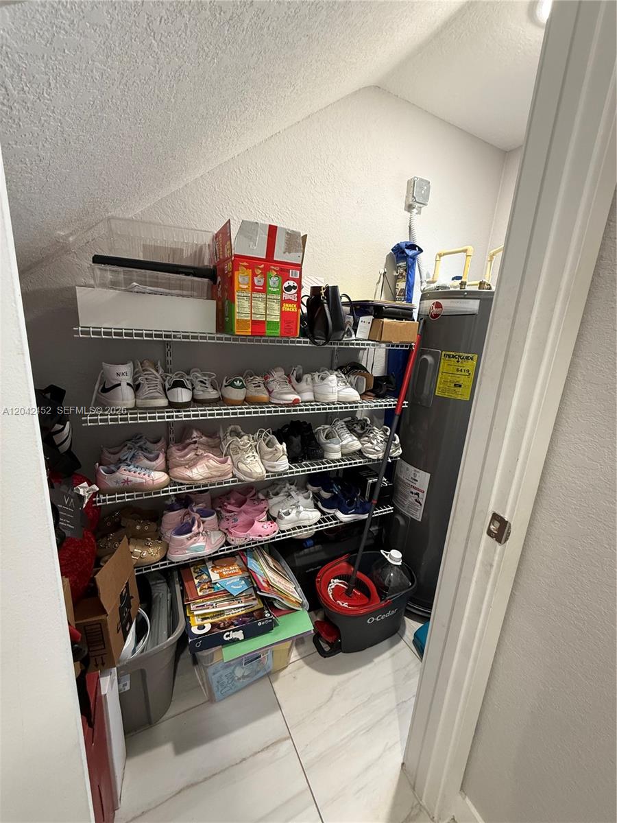 A utility closet contains wire shelving filled with shoes, boxes, and a water heater — 1034 SE 23rd Ter, Homestead FL 33035, HOMESTEAD, FL
