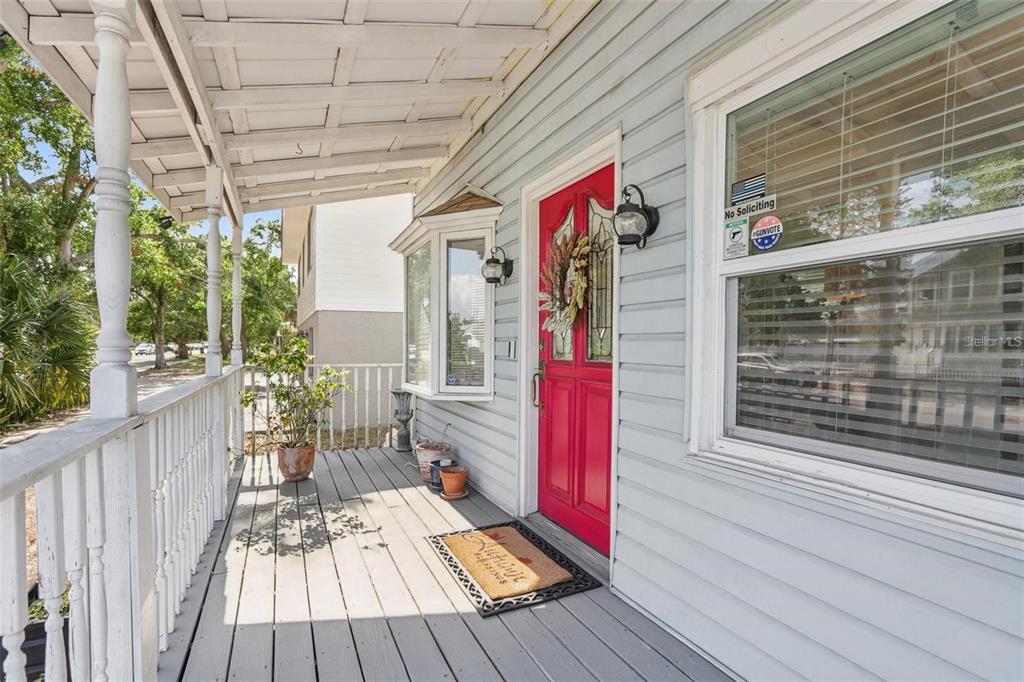A covered wooden front porch features a bright red door and a bay window — 757 32ND AVENUE N, ST PETERSBURG, FL