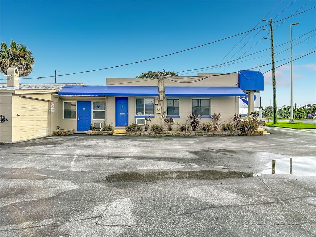 A single-story commercial building with blue awnings and two blue doors sits on a parking lot — 7429 US HIGHWAY 19, NEW PORT RICHEY, FL