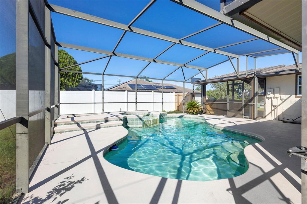 A screened-in patio features a swimming pool with an attached spa and concrete decking — 3307 CALDWELL STREET, DELTONA, FL