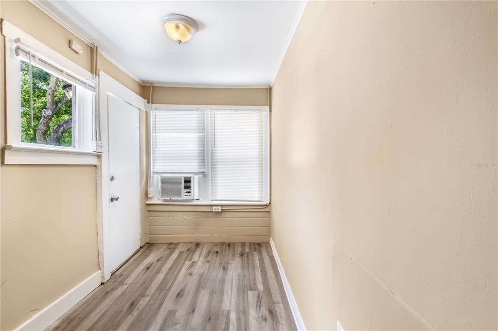 A small room with light-colored walls, wood-look flooring, a window air conditioner, and a door — 418 E AMELIA AVENUE UNIT G, TAMPA, FL