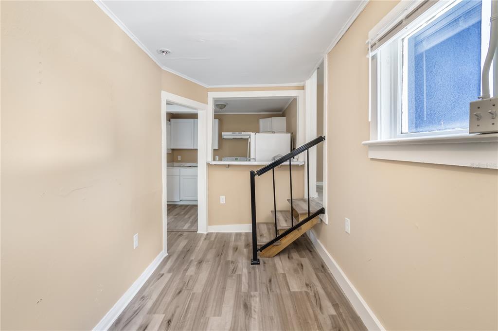 A room with light-colored walls, wood-look flooring, a staircase, and a view into a kitchen — 418 E AMELIA AVENUE UNIT G, TAMPA, FL