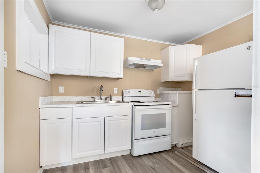 A kitchen features white cabinets, a white stove, a white refrigerator, and wood-look flooring — 418 E AMELIA AVENUE UNIT G, TAMPA, FL
