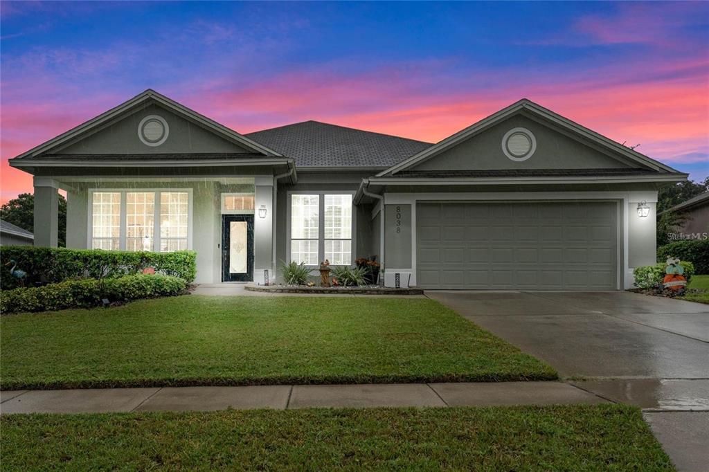 A single-story suburban house with a gray exterior, two front gables, and a concrete driveway — 8038 GLITTER COURT, ORLANDO, FL