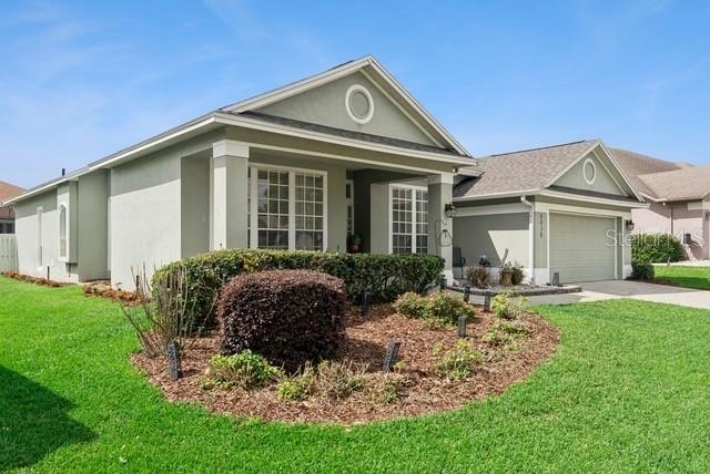 A single-story house with a light green exterior, a front porch, and an attached garage — 8038 GLITTER COURT, ORLANDO, FL