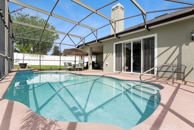 A screened-in swimming pool sits on a patio next to a house with sliding doors — 8038 GLITTER COURT, ORLANDO, FL