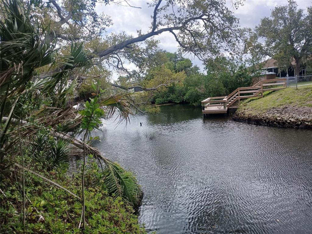 A wooden deck and staircase sit along the edge of a narrow, tree-lined canal — CORSICA LANE, NORTH PORT, FL