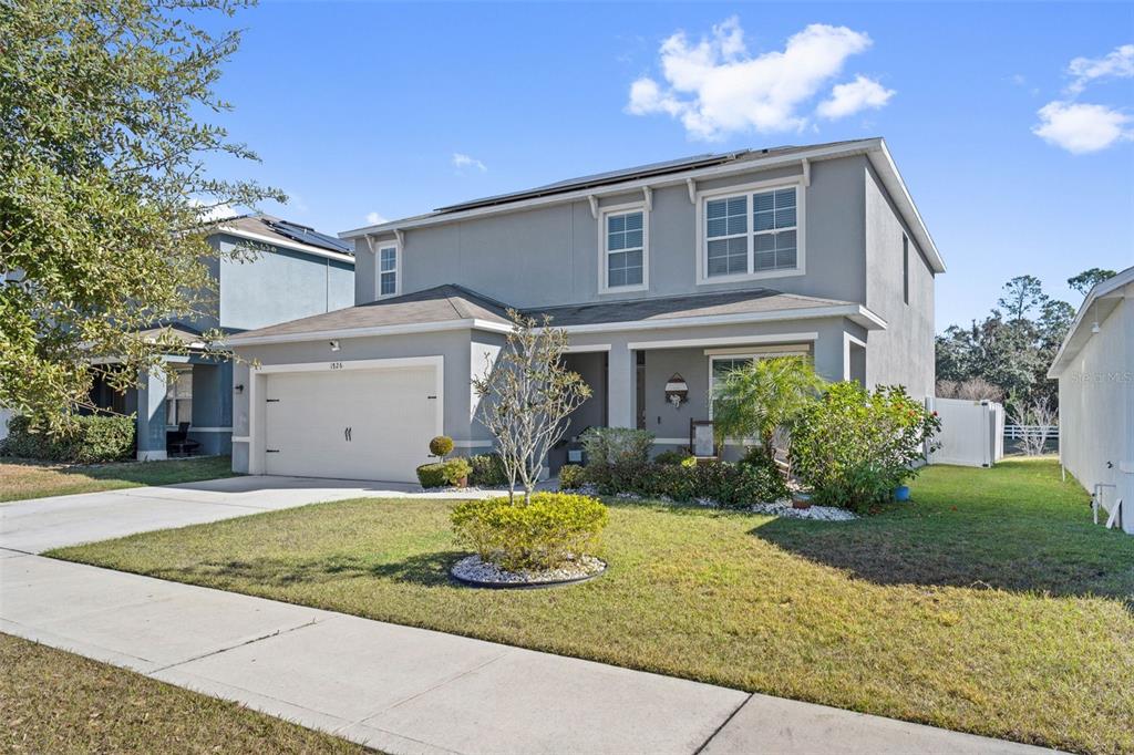 A two-story suburban house with a garage and a lawn at sunset — 1526 WHITE HAWK WAY, GROVELAND, FL