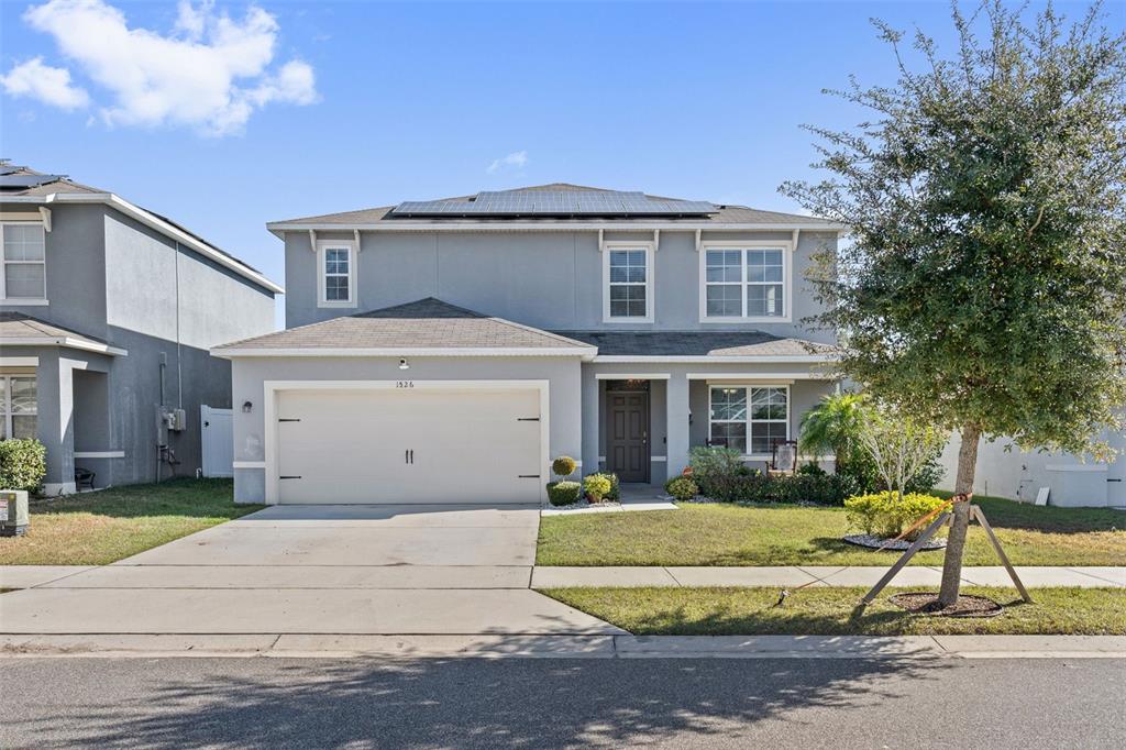A two-story house with a gray stucco exterior, a two-car garage, and solar panels — 1526 WHITE HAWK WAY, GROVELAND, FL