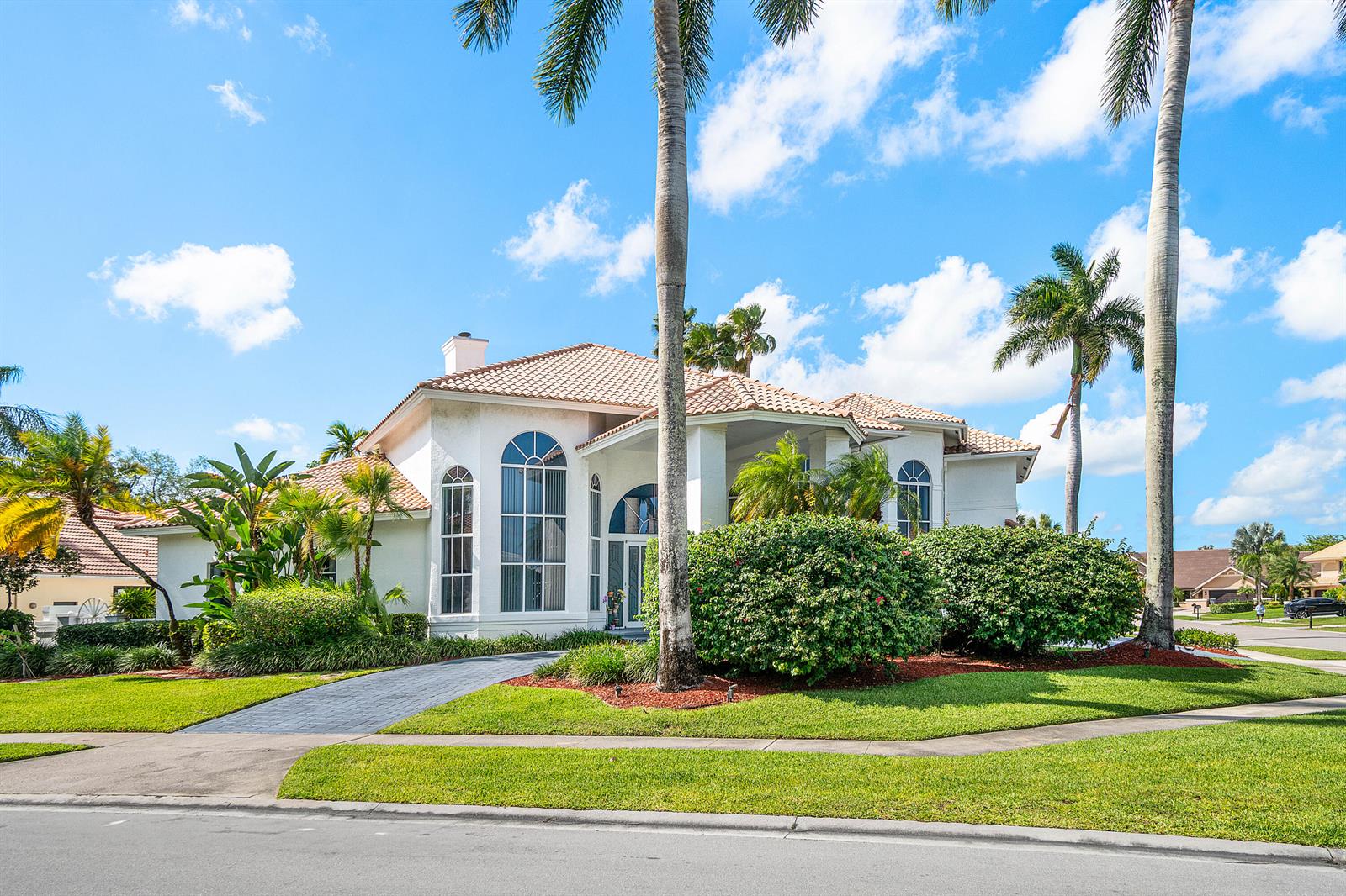 A white single-story house with a tiled roof, arched windows, and palm trees in front — 7173 Montrico Drive, Boca Raton FL 33433, BOCA RATON, FL