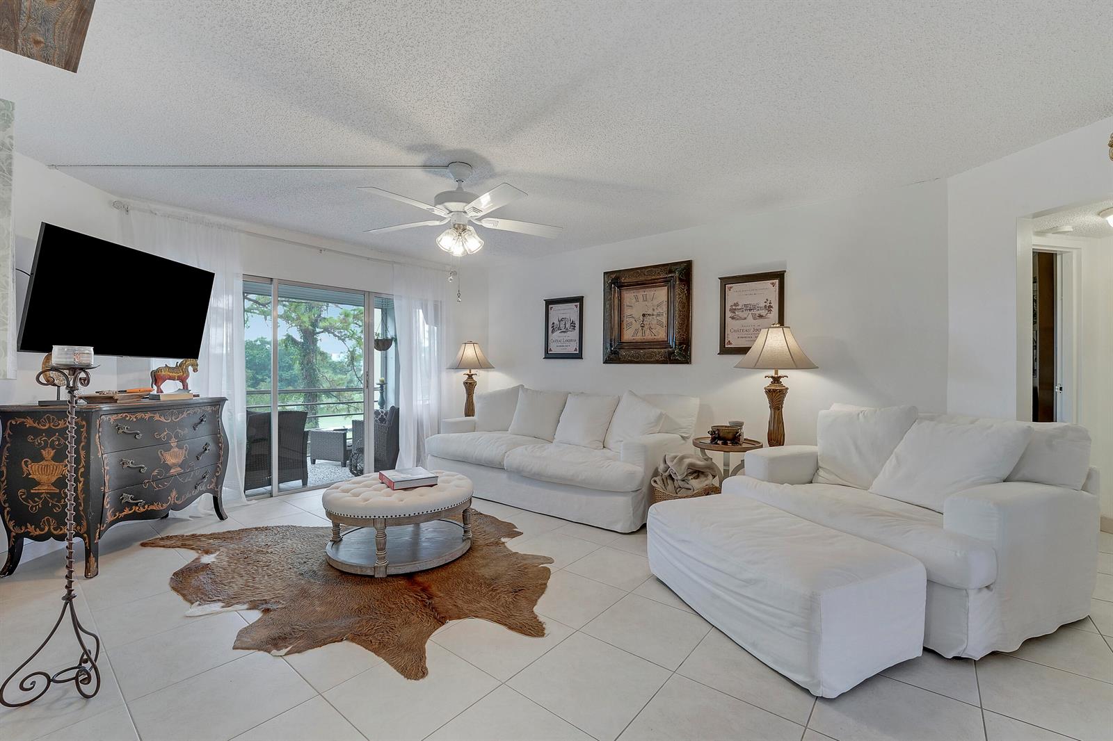 A living room features white sofas, a cowhide rug, and a sliding door to a balcony — 3755 Via # 405, Lake Worth FL 33467, LAKE WORTH, FL