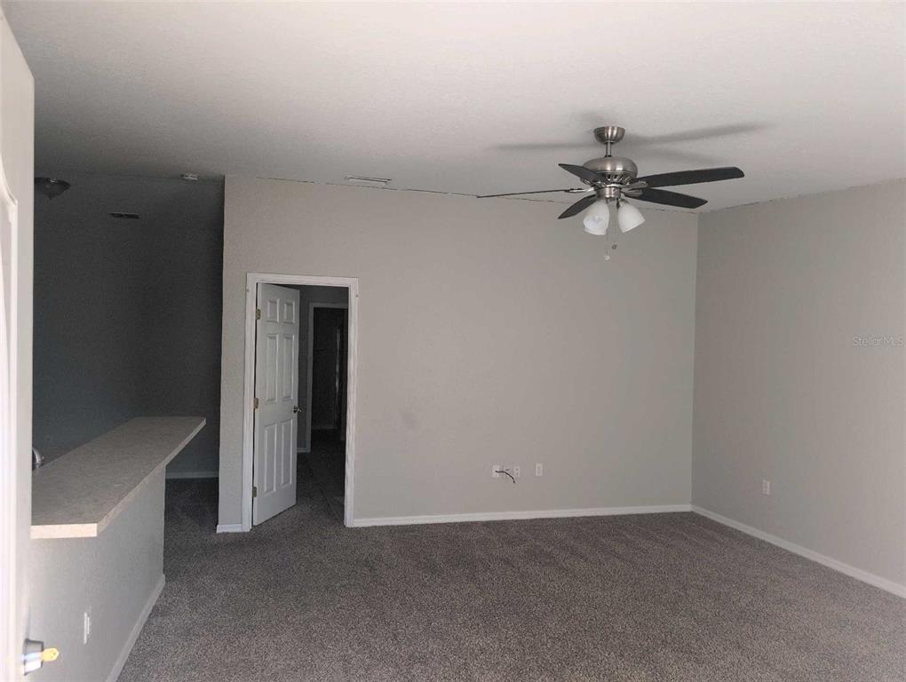 A carpeted living room features a ceiling fan, light gray walls, and an open doorway — 2145 SANDY HOOK, LAKELAND, FL