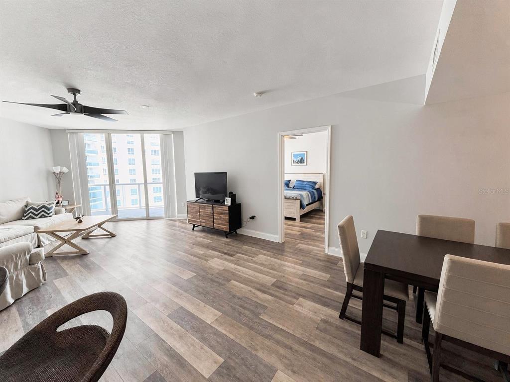 An open-concept living and dining area features wood-look flooring and a view of high-rise buildings — 231 RIVERSIDE DRIVE UNIT 1106-1, DAYTONA BEACH, FL