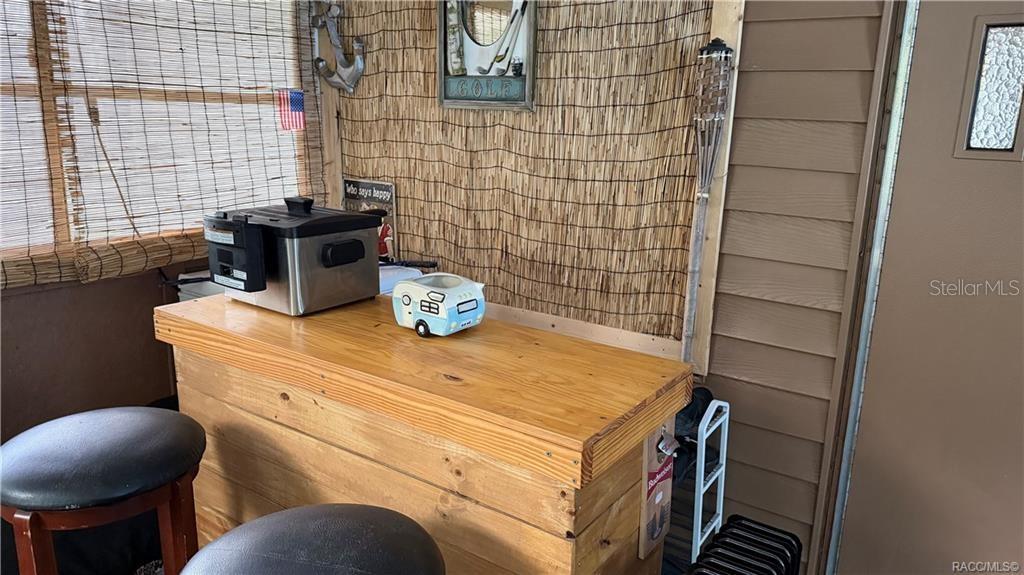 A wooden bar with a deep fryer and a small camper figurine sits on a porch — 5282 W BLADE LANE, DUNNELLON, FL
