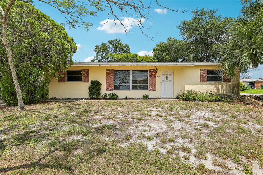 A single-story house with a yellow exterior, brick accents, and a large front yard — 1806 DODGE CIRCLE, MELBOURNE, FL