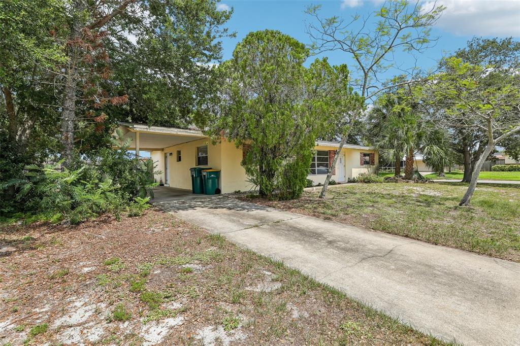 A single-story yellow house with a carport and a concrete driveway sits on a lot — 1806 DODGE CIRCLE, MELBOURNE, FL
